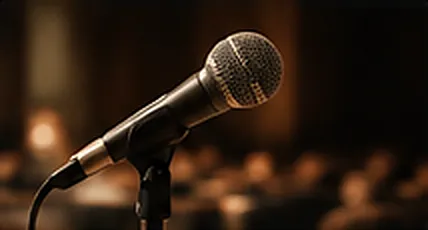 A microphone on a stand in front of a softly lit audience